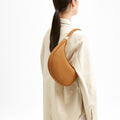 Luna Bag in tan textured leather with gold hardware, worn on the shoulder by a model.