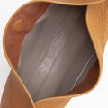 Close-up of the opening of a brown pebbled leather Luna Bag, showing the grey interior lining with visible stitching.