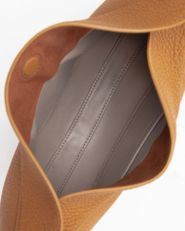Close-up of the opening of a brown pebbled leather Luna Bag, showing the grey interior lining with visible stitching.