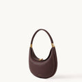 Burgundy leather Luna Bag with gold hardware and adjustable strap, designed for shoulder or crossbody wear.