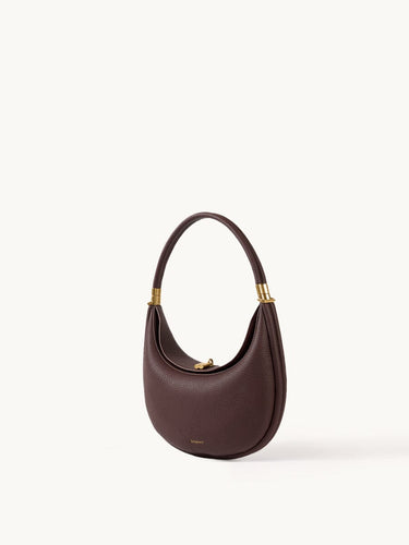Burgundy leather Luna Bag with gold hardware and adjustable strap, designed for shoulder or crossbody wear.