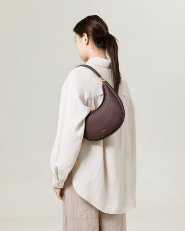 Burgundy Luna Bag, pebble-grain leather crossbody bag with adjustable strap.