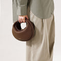 Chocolate brown pebbled leather Luna Bag with gold clasp, 'Songmont' logo visible. Textured leather handbag.