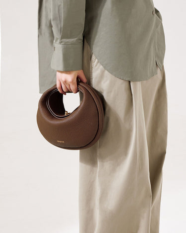 Chocolate brown pebbled leather Luna Bag with gold clasp, 'Songmont' logo visible. Textured leather handbag.