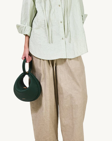 Emerald green pebbled leather Luna Bag with unique crescent shape and loop handle.
