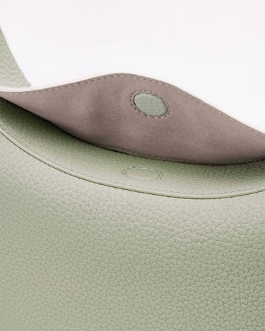 Mint green pebbled leather Luna Bag interior flap with grey suede lining and magnetic snap closure.