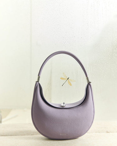 Lavender Luna Bag: Full-grain leather handbag with silver hardware and crescent shape, featuring dragonfly accent.