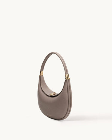 Taupe pebbled leather Luna Bag with a curved silhouette and gold hardware.
