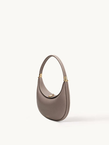 Taupe pebbled leather Luna Bag with a curved silhouette and gold hardware.
