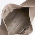 Interior view of a taupe pebbled leather Luna Bag, showing a suede-lined compartment with stitching.