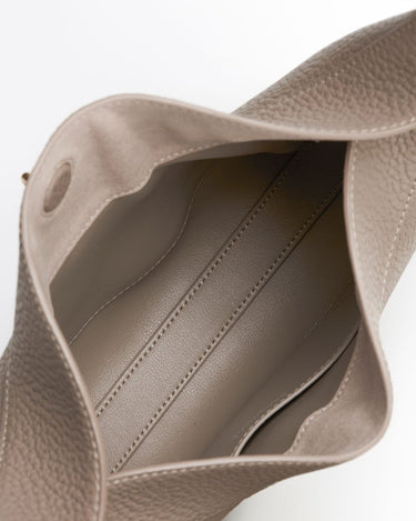 Interior view of a taupe pebbled leather Luna Bag, showing a suede-lined compartment with stitching.