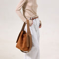 Medium Drippy Tote Bag in Caramel suede with leather straps. Model wears beige top and light jeans.