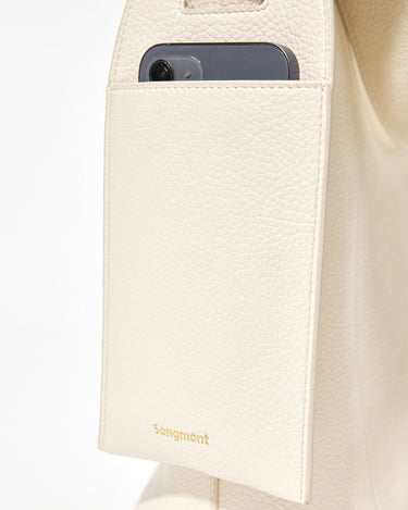 Cream vegan leather tote bag with exterior phone pocket featuring the Songmont logo.