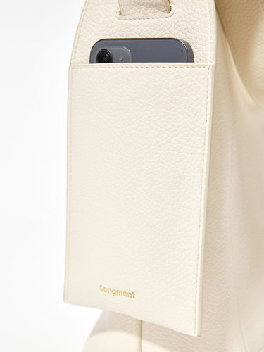 Cream vegan leather tote bag with exterior phone pocket featuring the Songmont logo.