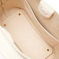 Beige vegan leather tote bag interior, showing main compartment and divider with brass studs.