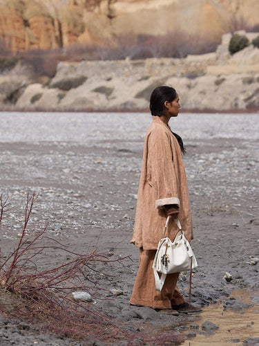 A woman in a tan outfit holds a white Medium Gather Bag Set with a beaded charm.
