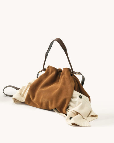 Ochre suede medium Gather Bag set with beige garment spilling out, showcasing its spacious design.