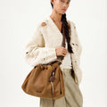 Ochre suede medium gather bag set on woman, showcasing its slouchy design and leather accents.