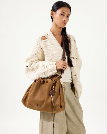 Ochre suede medium gather bag set on woman, showcasing its slouchy design and leather accents.