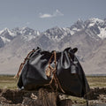 Medium Gather Bag Set in Onyx black leather with crystal charm, mountains background.