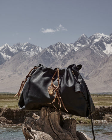 Medium Gather Bag Set in Onyx black leather with crystal charm, mountains background.