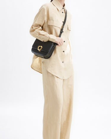 Black leather Medium Reset Tofu Bag with gold buckle, worn by a woman in tan linen outfit.