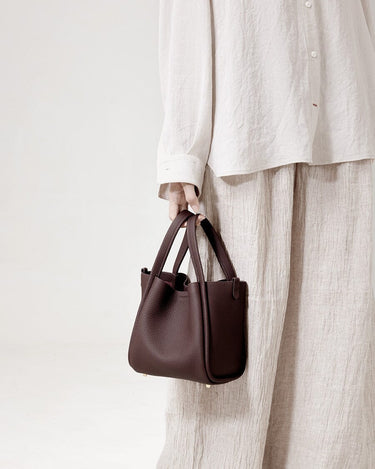 Medium burgundy Song Bag in pebble leather with gold hardware. Structured design, ideal for work and travel.