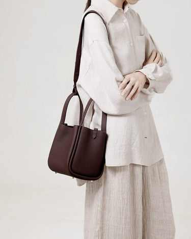 Medium Song Bag in burgundy pebbled leather with adjustable strap, worn crossbody by a woman.