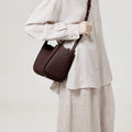 Medium Song Bag in burgundy full-grain leather with adjustable strap, worn by a model.