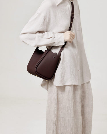 Medium Song Bag in burgundy full-grain leather with adjustable strap, worn by a model.