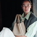 Medium Song Bag in Cream Apricot leather, held by a woman in casual attire.