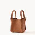 Medium Song Bag in rich brown pebbled leather with dual top handles and gold-tone hardware.