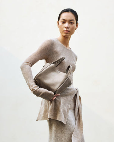 Medium Song Bag in Haze nubuck leather, with top handles and a structured design, held by a model.