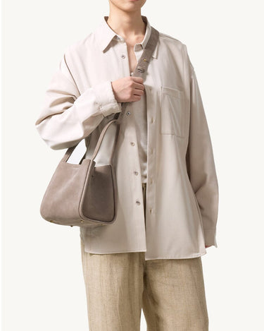 Medium Song Bag in Haze nubuck leather, worn by a person in a neutral outfit.
