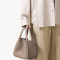 Medium Song Bag in Haze, matte-finish nubuck leather with O-shaped structure and magnetic closure.