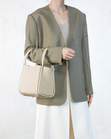 Ivory pebbled leather Medium Song Bag with single handle and flap closure. Chic everyday style.