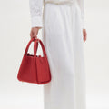 Medium Song Bag in Lucky Red pebbled leather with twin top handles and metallic base studs.