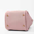 Pink leather Song Bag with gold feet and brand logo, showing bottom detail.