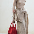 Medium Song Bag in poppy red nubuck, structured tote with dual handles and gold feet, worn with neutral knit.