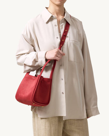 Medium Song Bag in Poppy red leather, featuring textured finish and gold hardware, worn by a model.