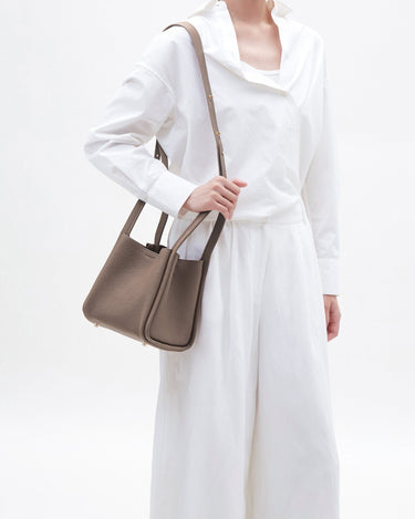 Medium Song Bag in taupe full-grain leather with adjustable strap. Elegant leather bucket bag for women.