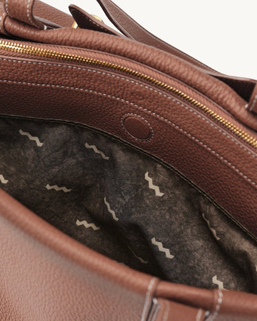 Medium Yore Duffle Bag interior, golden brown full-grain leather, white stitching, gold zipper, abstract wave lining