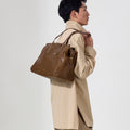 Medium Yore Duffle Bag in Sandal color, made of vegetable-tanned leather, worn by a man.