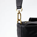 Black leather duffle bag with gold clasp detail and embossed 'songmont' logo on shoulder strap