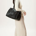 Medium Yore Duffle Bag in Onyx vegan leather worn by a woman. Features textured finish and gold hardware.