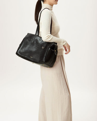 Medium Yore Duffle Bag in Onyx vegan leather worn by a woman. Features textured finish and gold hardware.