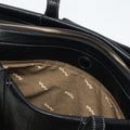 Medium Yore Duffle Bag in Onyx, black vegan leather with white stitching and wave-patterned tan lining. Features gold zipper.