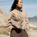 Medium Yore Hobo Bag in Cobble Grain leather, worn by a woman in a suede jacket in a desert landscape.