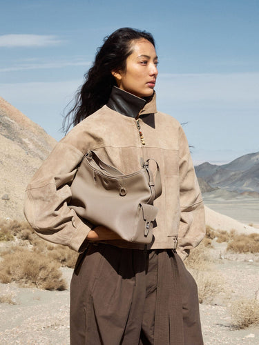 Medium Yore Hobo Bag in Cobble Grain leather, worn by a woman in a suede jacket in a desert landscape.