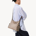 Medium Yore Hobo Bag in Cobble Grain textured leather, worn over the shoulder by a woman in a blue striped shirt.